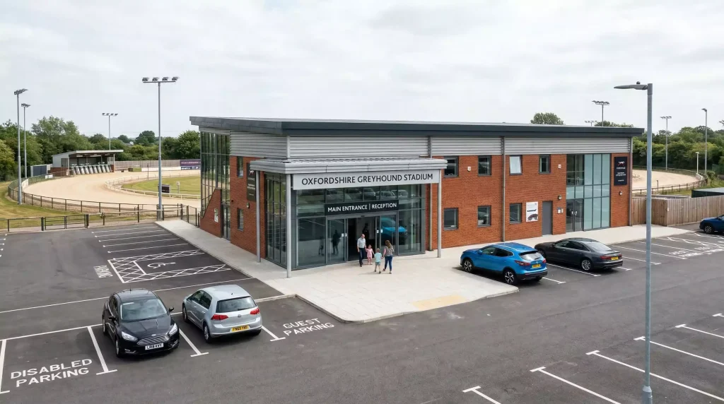 Modern greyhound stadium building with corporate signage and a well-maintained racing circuit